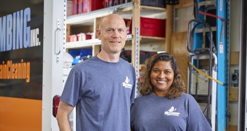 TJK Plumbing’s owners standing together beside their service truck